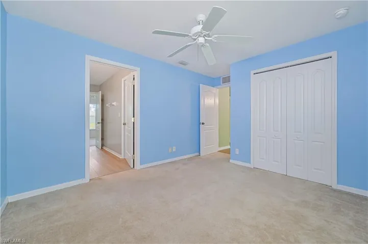 Unfurnished bedroom with ceiling fan, a closet, and light colored carpet