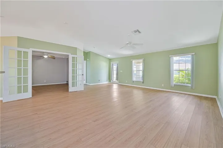 Empty room featuring vaulted ceiling, ceiling fan, light hardwood / wood-style floors, and french doors