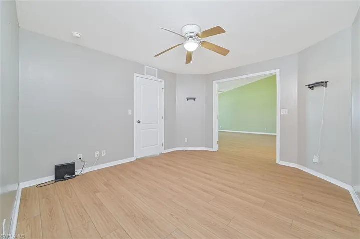 Empty room with ceiling fan and light hardwood / wood-style flooring