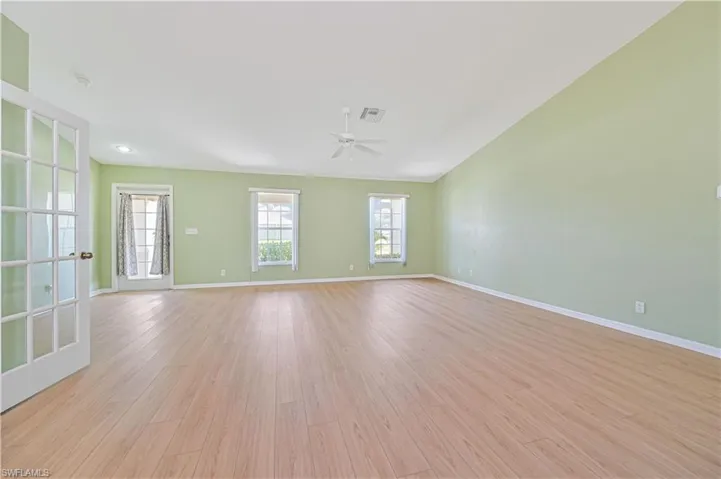 Empty room with french doors, light wood-type flooring, and ceiling fan