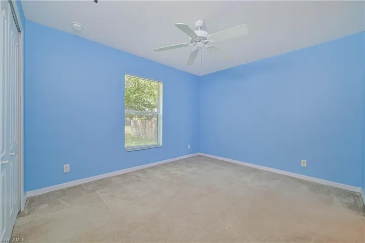 Carpeted empty room featuring ceiling fan