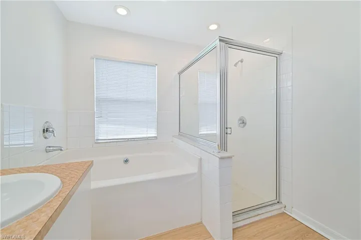 Bathroom featuring shower with separate bathtub, hardwood / wood-style floors, and vanity