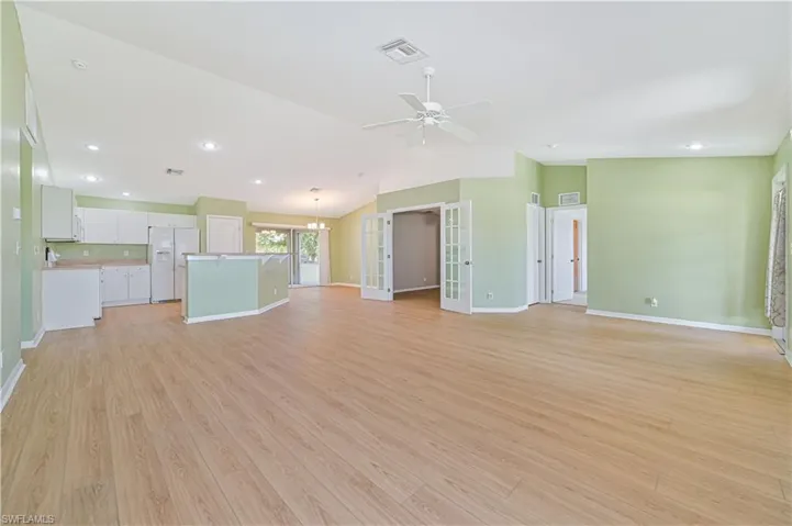 Unfurnished living room with ceiling fan, light hardwood / wood-style flooring, french doors, and vaulted ceiling