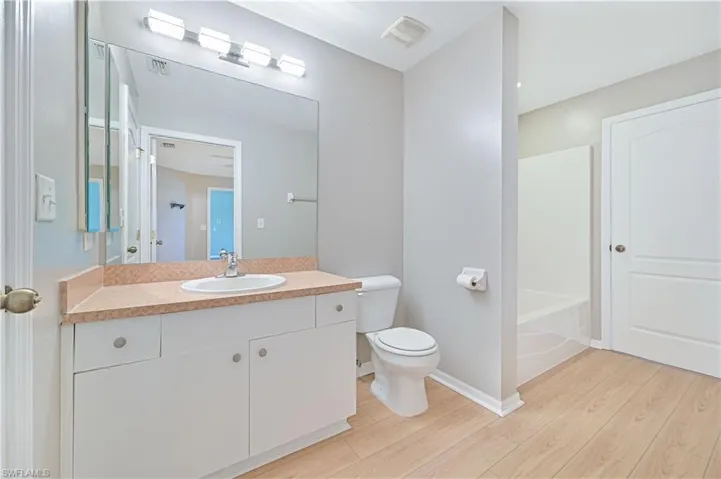 Full bathroom with bathing tub / shower combination, hardwood / wood-style floors, toilet, and large vanity
