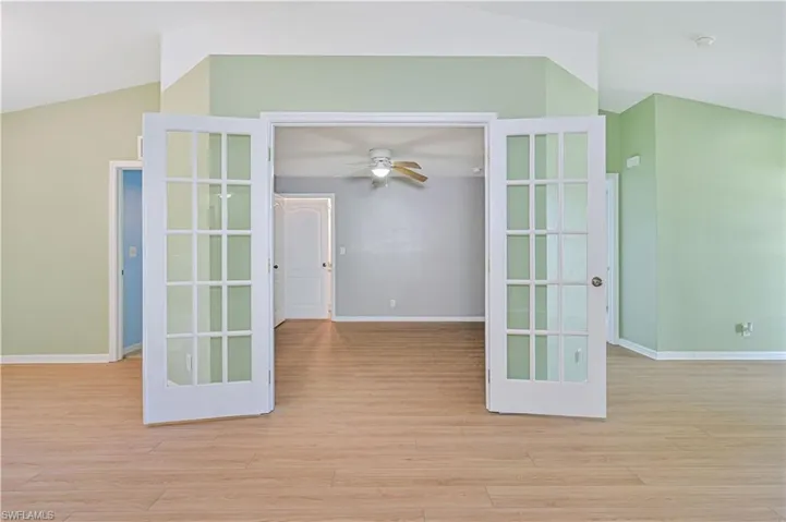 Spare room featuring ceiling fan, light hardwood / wood-style floors, french doors, and lofted ceiling