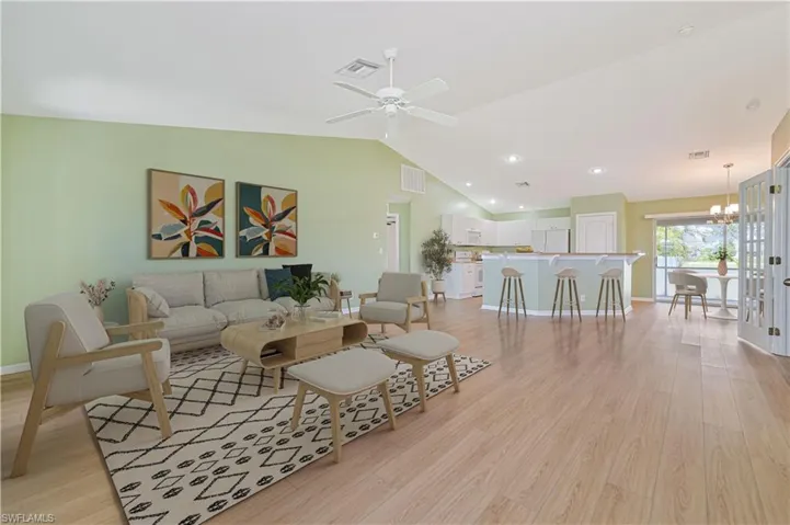 Living room with light hardwood / wood-style floors, lofted ceiling, and ceiling fan with notable chandelier
