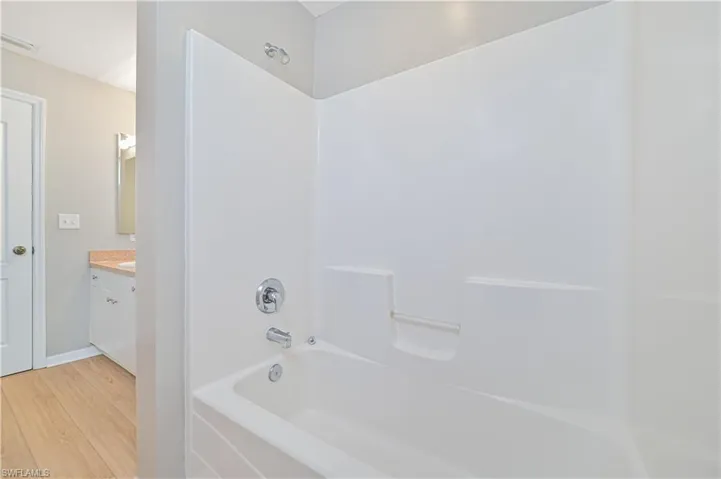Bathroom featuring washtub / shower combination, hardwood / wood-style floors, and vanity
