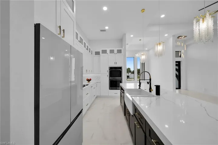 Kitchen with glass insert cabinets, fridge, white cabinets, light marble finish flooring, and pendant lighting