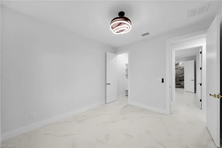 Unfurnished bedroom featuring light marble finish flooring and a spacious closet