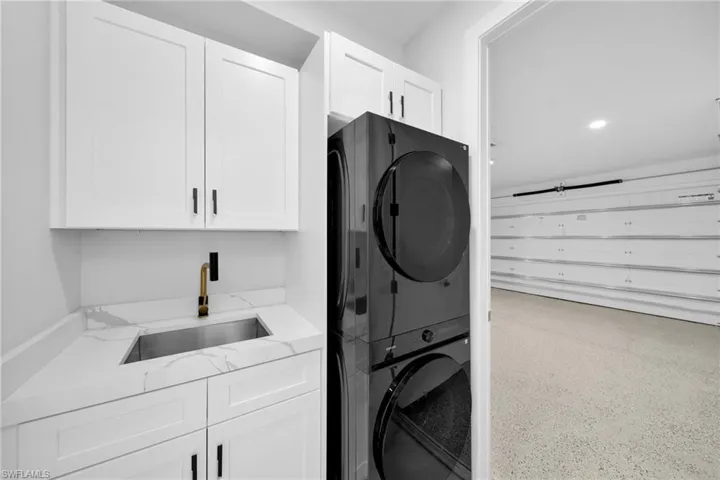 Laundry room with cabinet space, estacked washer and dryer, and dark speckled floor