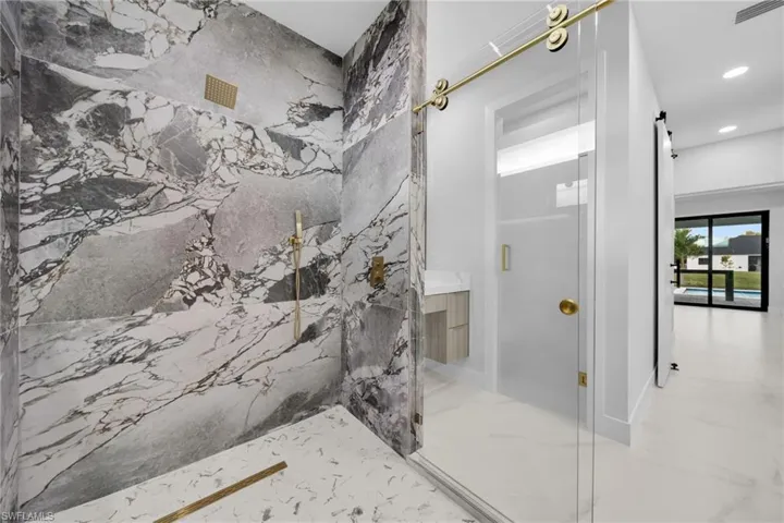 Bathroom featuring a marble finish shower, marble tiled floors, and recessed lighting