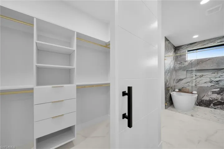 Full bath featuring light marble finish flooring and a walk in closet