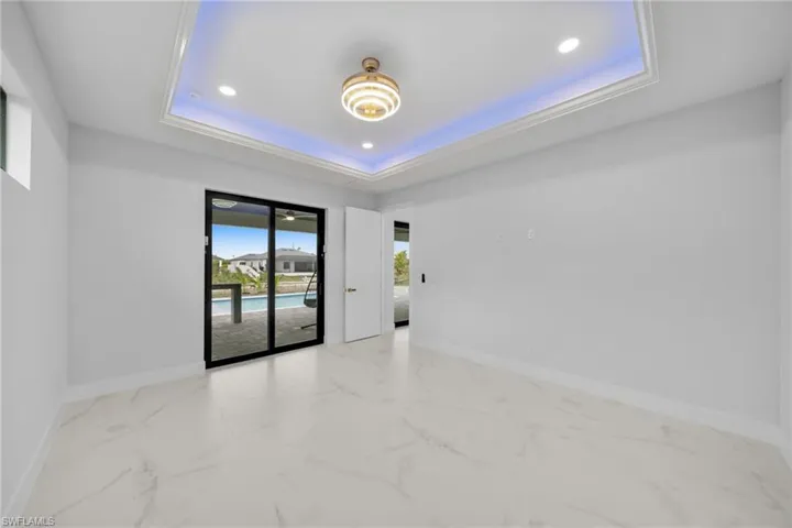 Empty room featuring light marble finish flooring, recessed lighting, and a tray ceiling