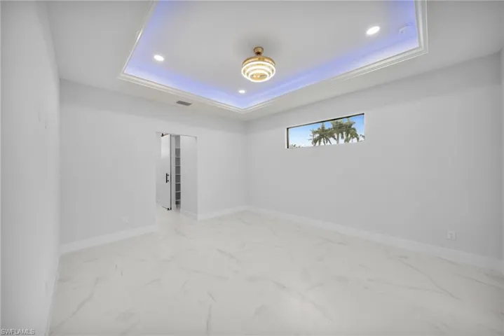 Unfurnished room with light marble finish floors, recessed lighting, and a tray ceiling