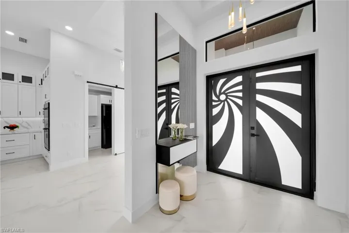 Foyer entrance featuring a barn door, light marble finish flooring, and recessed lighting