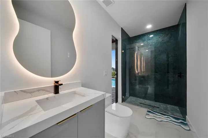 Bathroom with marble look tile flooring, a stall shower, vanity, and recessed lighting