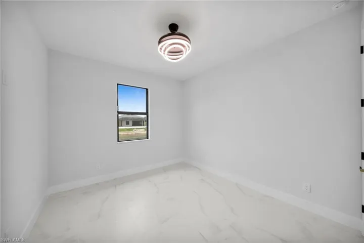 Empty room featuring light marble finish flooring and baseboards