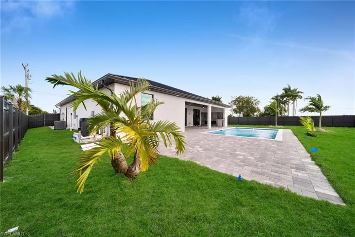 Rear view of house featuring a fenced backyard, stucco siding, and a patio area