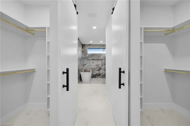Spacious closet with a barn door and light marble finish flooring
