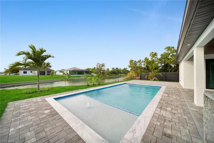 View of swimming pool featuring a patio area, a fenced backyard, and a water view