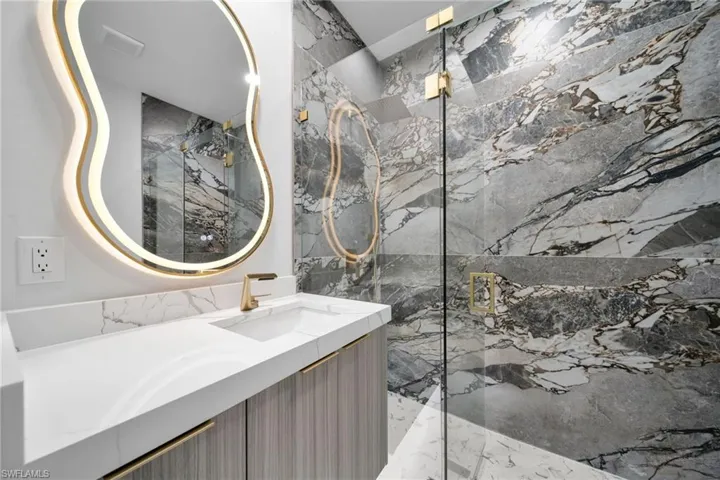 Bathroom featuring a marble finish shower and vanity