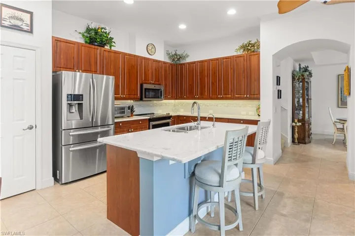 Kitchen featuring appliances with stainless steel finishes, a sink, arched walkways, decorative backsplash, and recessed lighting