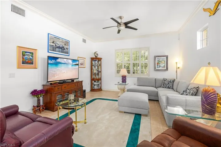 Living area featuring a ceiling fan, plenty of natural light, ornamental molding, and tile patterned floors