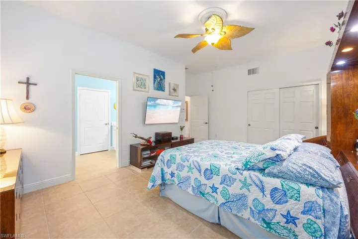 Bedroom featuring light tile patterned floors, a closet, baseboards, and a ceiling fan