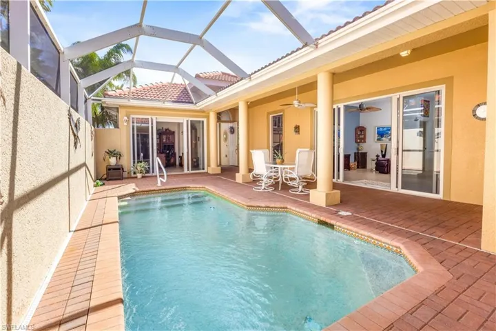 Outdoor pool with a patio area, a ceiling fan, and a lanai