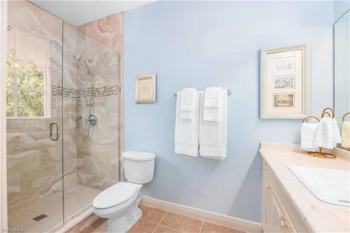 Bathroom with a shower stall, toilet, vanity, tile patterned floors, and baseboards
