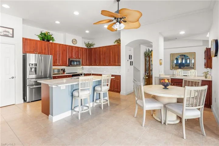 Kitchen featuring appliances with stainless steel finishes, recessed lighting, arched walkways, a center island with sink, and light countertops