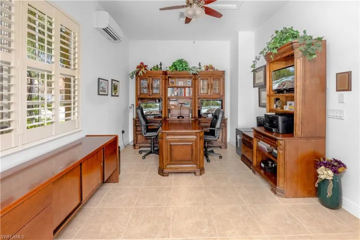Office area featuring an AC wall unit, a ceiling fan, light tile patterned flooring, and plenty of natural light