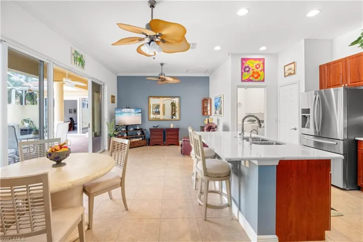 Kitchen featuring stainless steel refrigerator with ice dispenser, a sink, ceiling fan, ornamental molding, and a kitchen bar