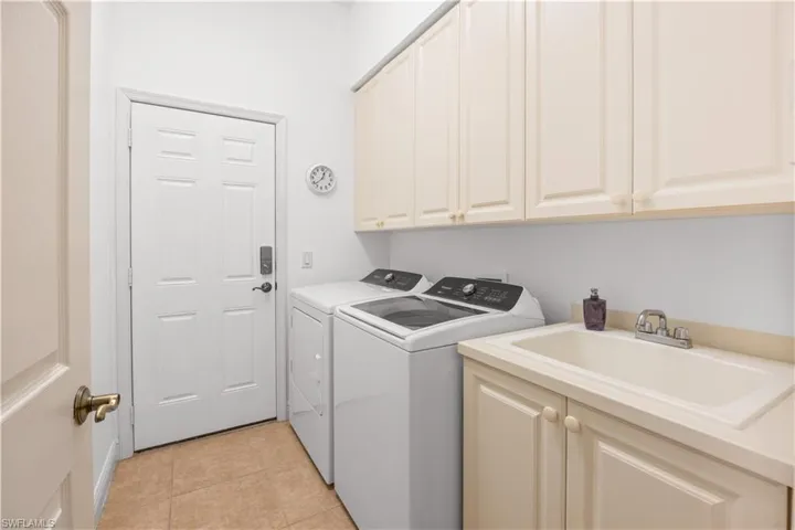Washroom with washer and clothes dryer, cabinet space, and light tile patterned floors