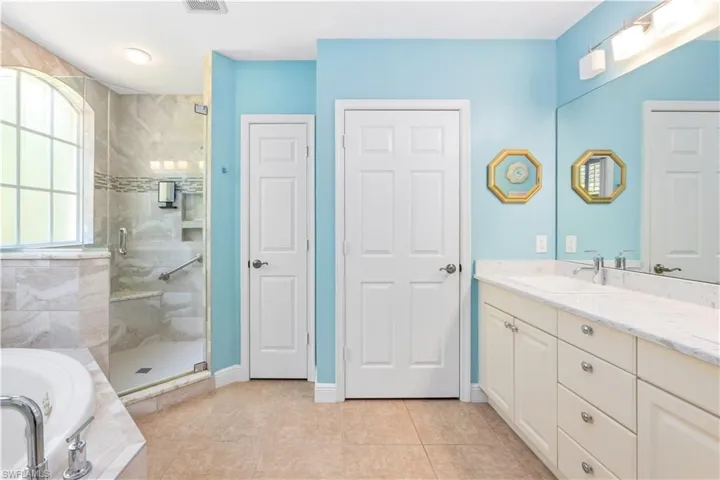 Full bathroom with a stall shower, a garden tub, vanity, and tile patterned flooring