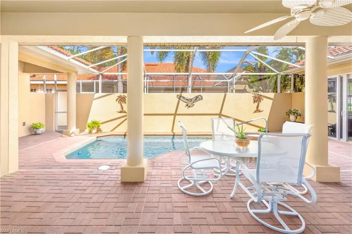 View of pool with a patio, glass enclosure, and a ceiling fan