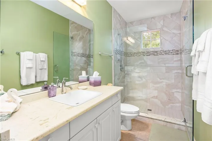 Bathroom featuring a shower stall, vanity, toilet, and tile patterned flooring
