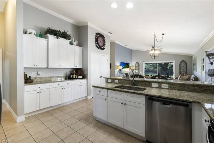 Kitchen with lofted ceiling, ornamental molding, white cabinetry, a sink, and dishwasher
