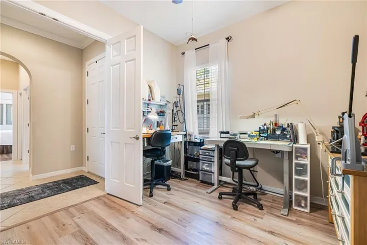 Bedroom, craft room or office featuring arched walkways, light wood-style flooring, and crown molding