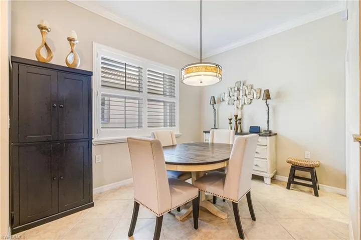 Dining room with crown molding and light tile patterned flooring