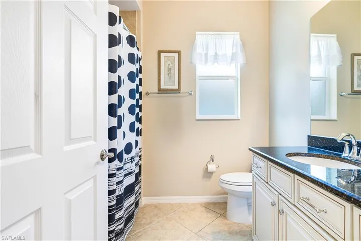 Full bathroom with a shower with shower curtain, light tile patterned flooring, and vanity