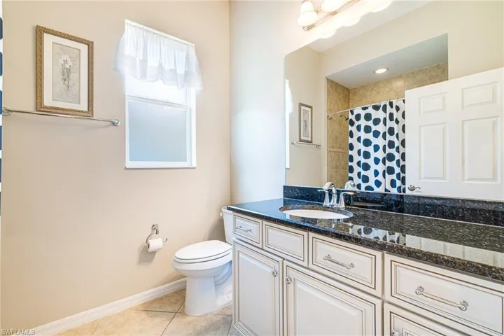 Full bath featuring vanity, light tile patterned floors, and curtained shower