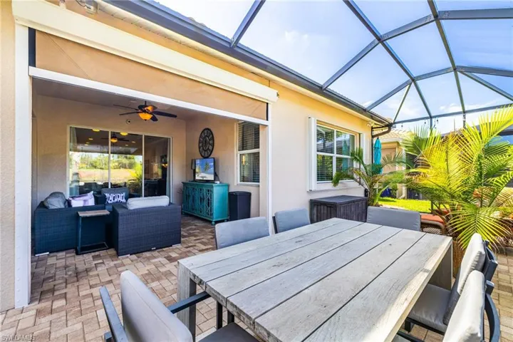 View of patio featuring outdoor dining area, a sunroom, outdoor lounge area, ceiling fan, and glass enclosure