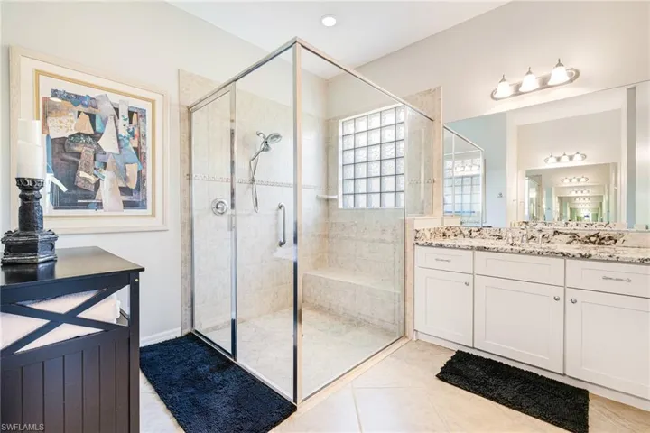 Bathroom with light tile patterned flooring, a shower stall, and vanity