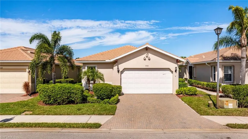 View of front facade with stucco siding, decorative driveway, and a garage
