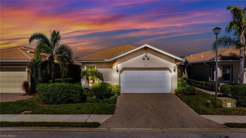 View of front of property featuring stucco siding, decorative driveway, a garage, and a tile roof