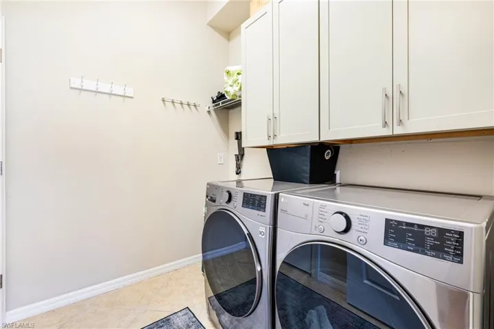 Washroom featuring washer and dryer, cabinet space, and light tile patterned flooring