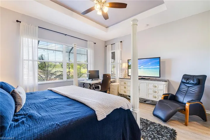 Bedroom with a tray ceiling, light wood-style floors, and ceiling fan