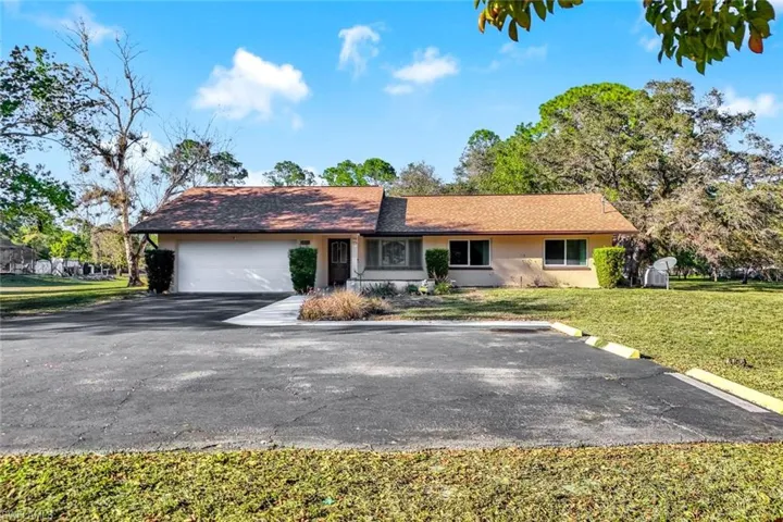 Ranch-style house with a garage, stucco siding, asphalt driveway, a front lawn, and a porch