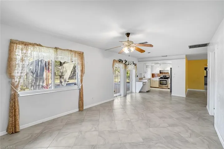 Unfurnished living room featuring a ceiling fan and baseboards